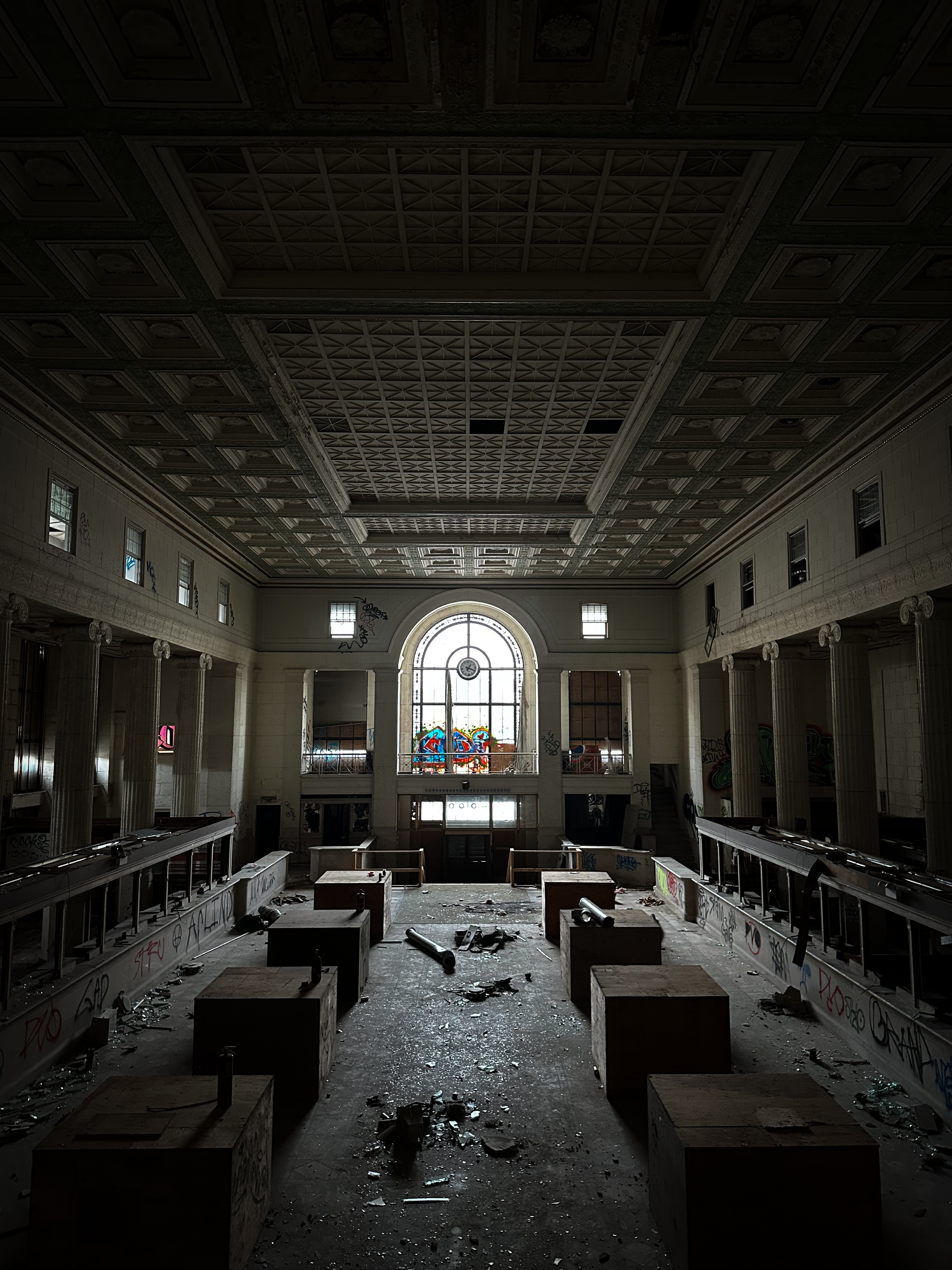 Large abandoned bank lobby with high ceiling and graffiti